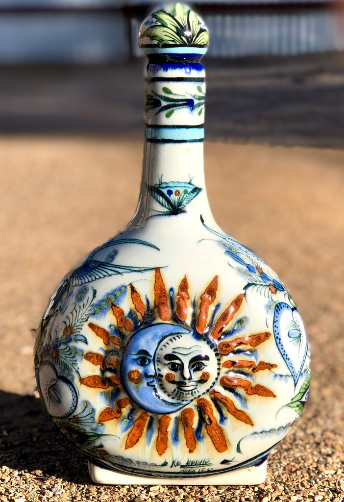Decorative ceramic bottle with sun and moon design on a sandy background