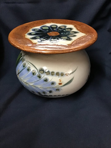 Ceramic pot with decorative lid on a dark background