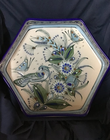 Decorative hexagonal plate with floral and bird design on a dark background