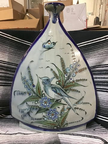 Decorative ceramic vase with bird and floral design on a striped surface