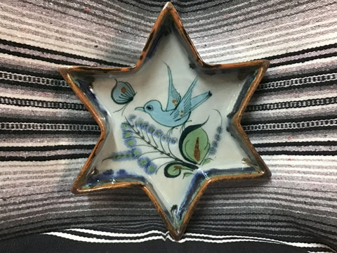 Star-shaped ceramic dish with bird design on a striped fabric background