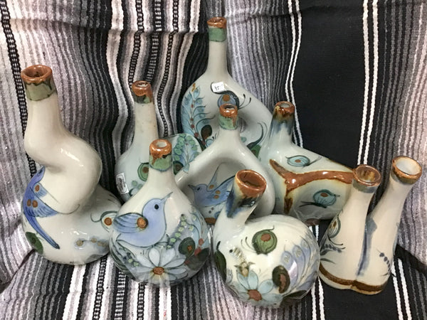 Collection of decorative ceramic bottles with artistic designs on a striped fabric background
