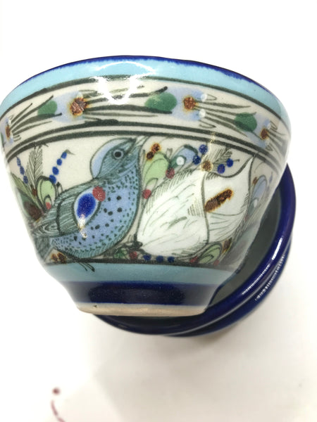 Ken Edwards collection series custard bown with blue rim. It is natural grey clay color background with birds, butterflies, and leaves in blue, green, black and brown on the outside.