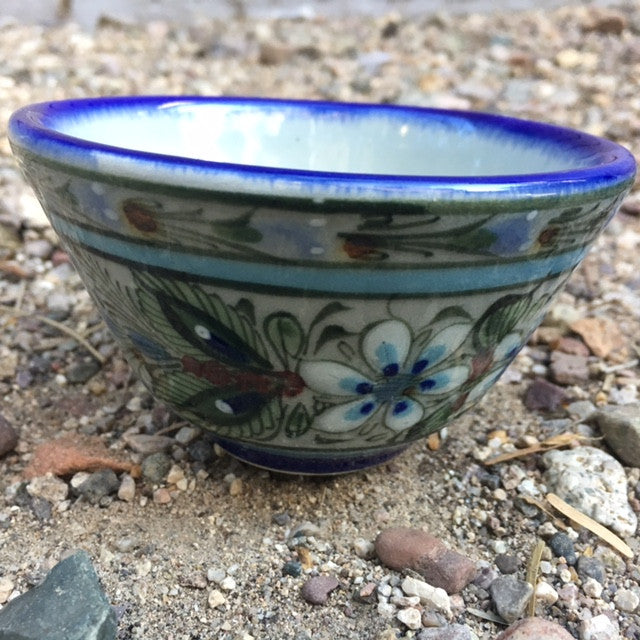Ken Edwards collection series custard bown with blue rim.  It is natural grey clay color background with birds, butterflies, and leaves in blue, green, black and brown on the outside. 