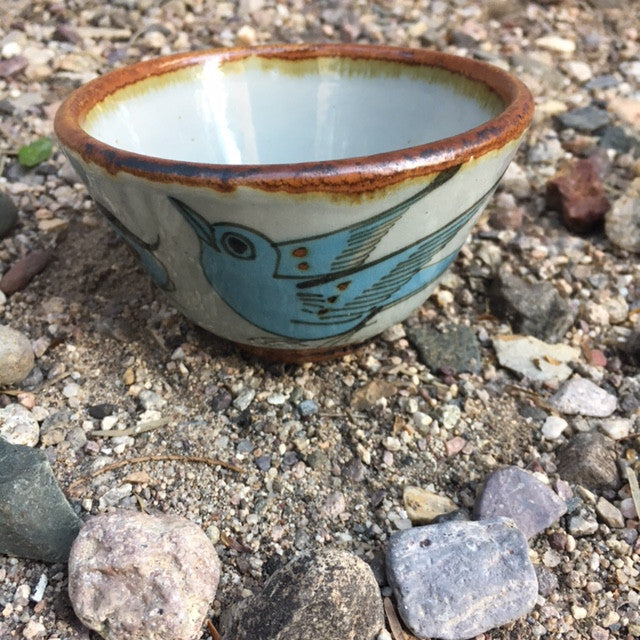 Ken Edwards custard or soup cup.  It is natural grey clay color background with birds, butterflies, and leaves in blue, green, black and brown on the outside.