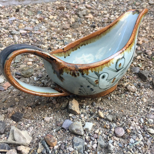 Ken Edwards Stoneware Pottery gravy boat with brown rim and colorful bird, butterfly, and leaf designs.